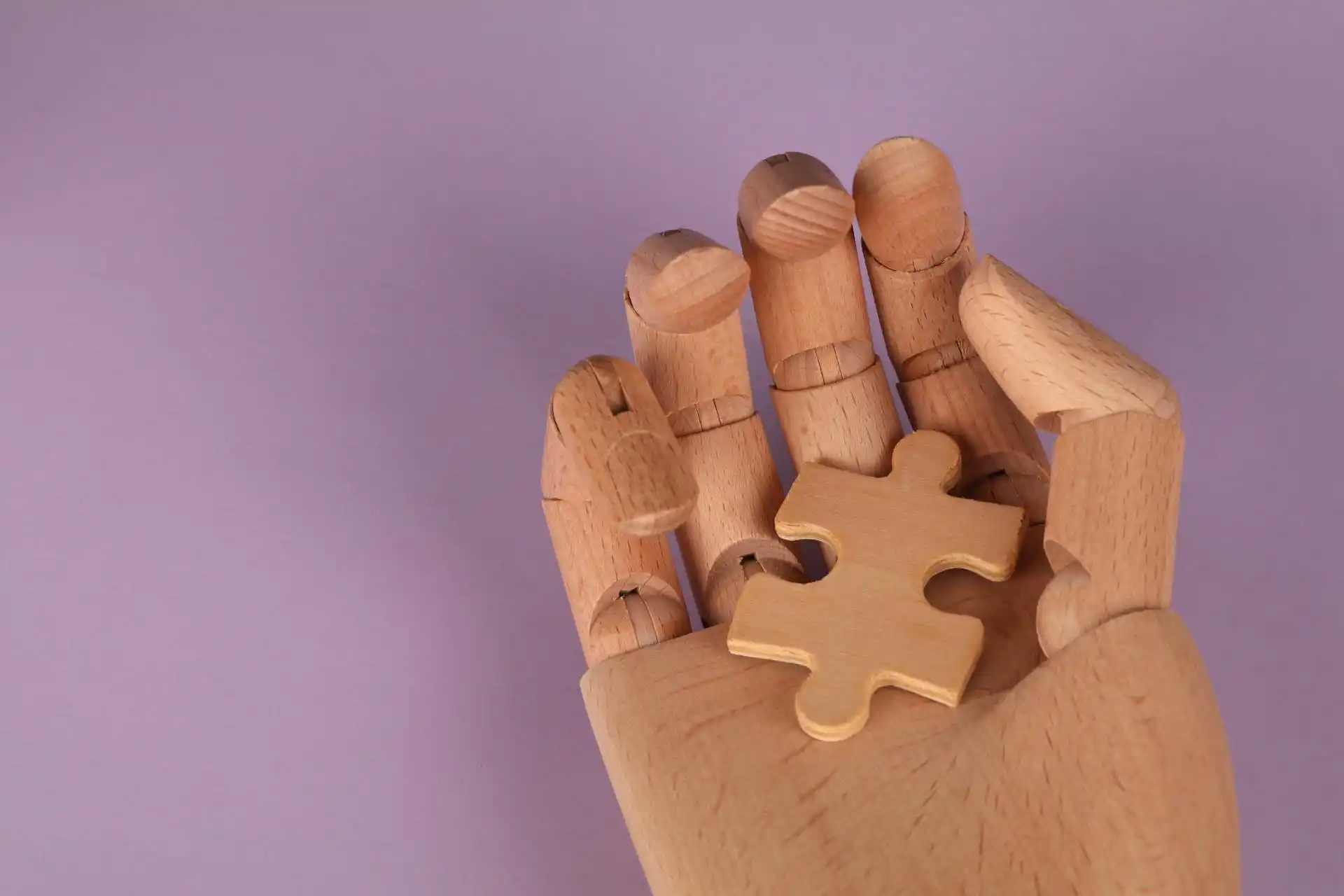 Puzzle Piece in a Wooden Hand